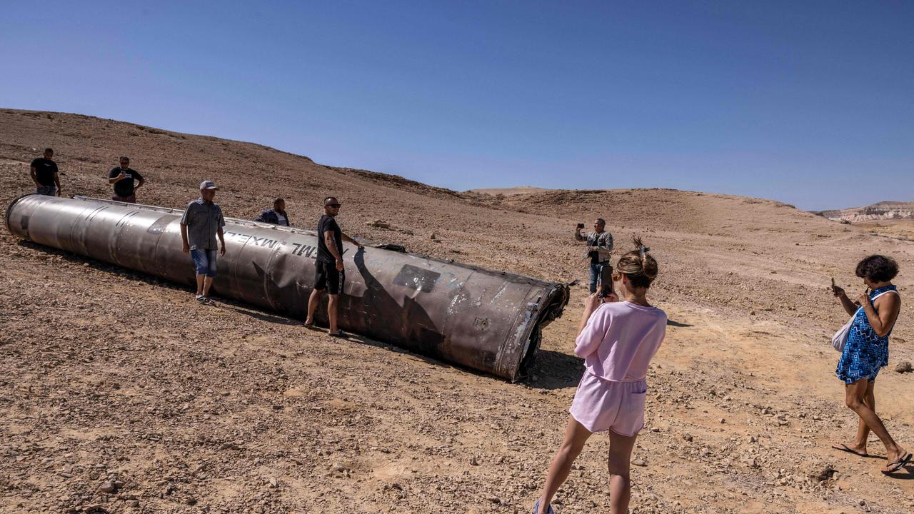 People pose for pictures at the site of the remains of an Iranian missile in the Negev desert near Arad. Picture: MENAHEM KAHANA / AFP.