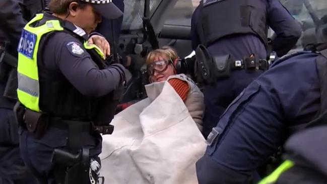 An anti-war protester cemented herself to a car in an attempt to disrupt the weapons expo in Melbourne on Friday morning. Picture: ABC