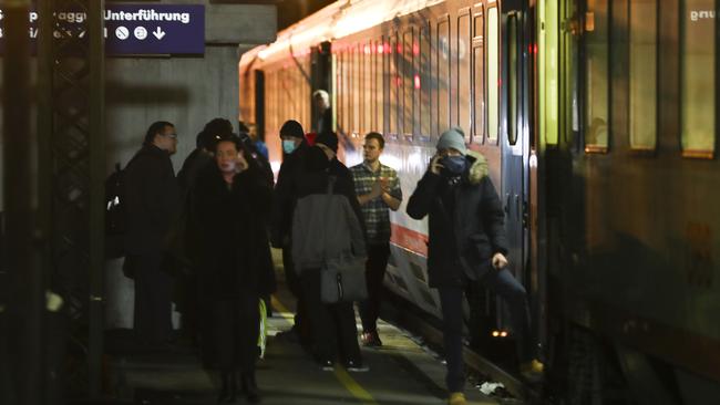 People stand beside a train stopped by authorities on the Italian side of the Brenner Pass, Italy, following fears a train had two people on board who may have been infected with coronavirus.