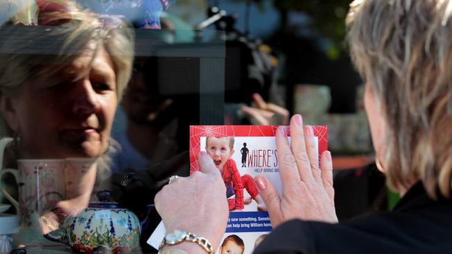 Hetty Johnston puts a poster of missing child William Tyrell in the window of a shop. Photo: Nathan Edwards