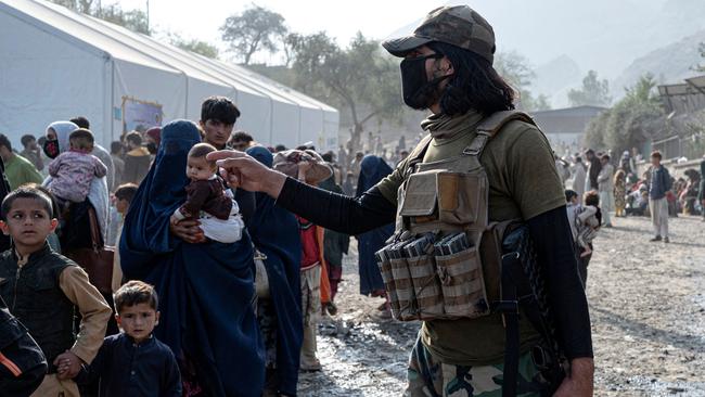 An Afghan security officer directs refugees as they arrive from Pakistan at the Torkham border crossin in Nangarhar on Thursday. Picture: AFP