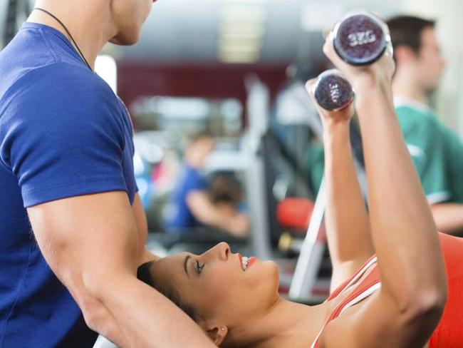 woman and Personal Trainer in gym, with dumbbells