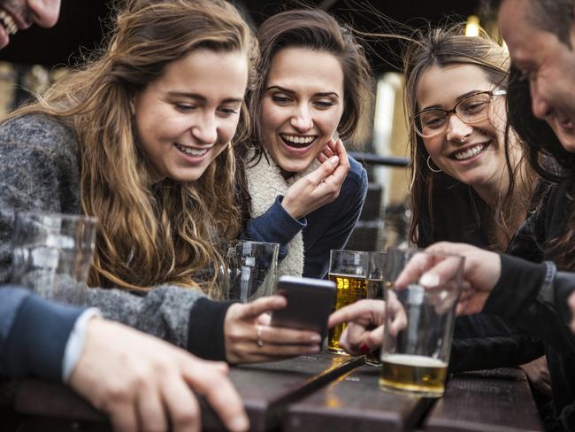 ESCAPE: UK Drink, Mikaella Clements -  Group of friends hanging out in a London Pub seated on the outdoor tables. Their drinking a mix of blonde and red beers and holding smartphones toasting together. . Picture: iStock