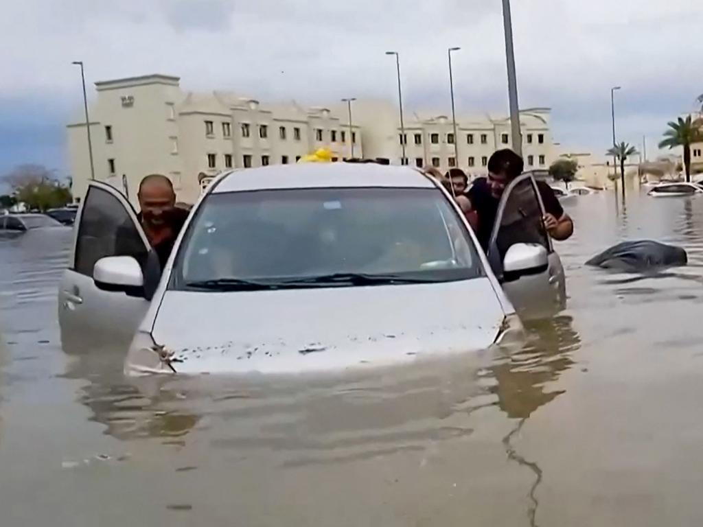 People push a stranded car along a flooded street in Dubai, Picture: AFP