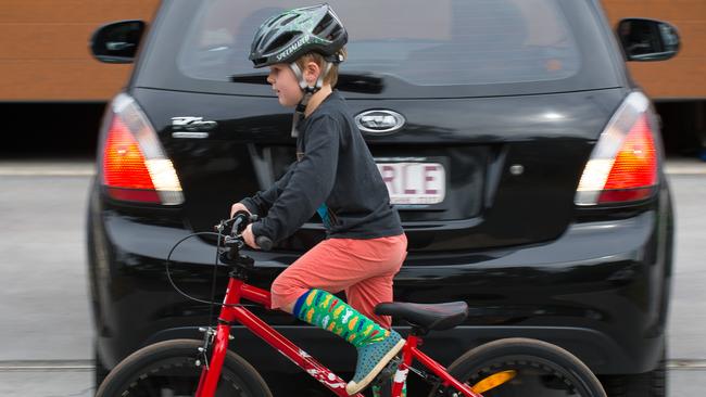 A young boy rides his bike behind a car. Picture: Paul Broben.