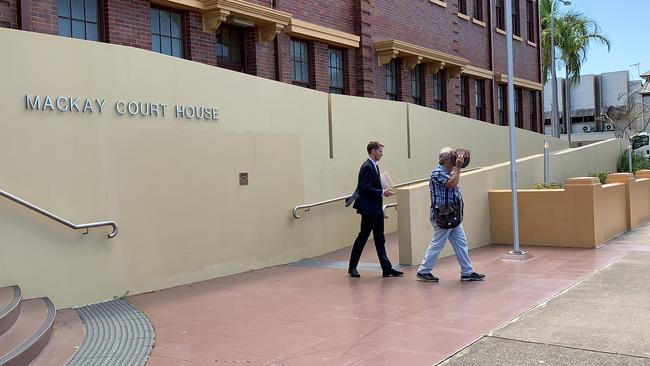 Errol Selwyn Damrow, who secretly filmed his NDIS carer naked when she rented a room at his property, shields his face as he leaves Mackay courthouse with his solicitor after pleading guilty to the charge.