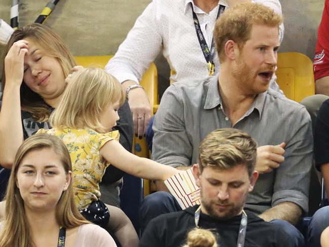 Quick! While he’s not looking ... 2-year-old Emily gets stuck into Harry’s popcorn. Picture: Chris Jackson/Getty Images for the Invictus Games Foundation