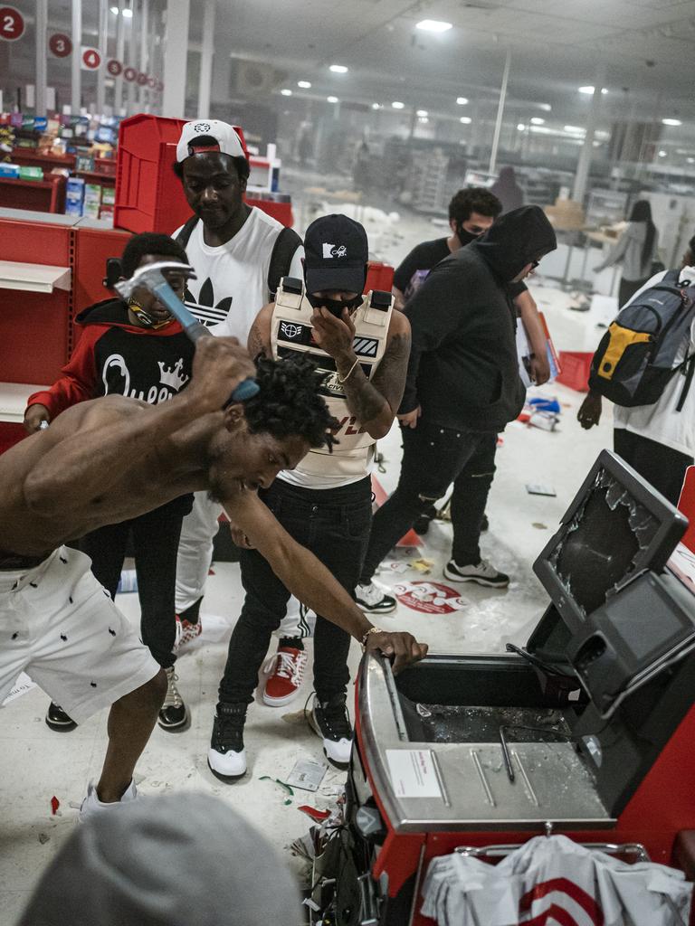 A looter uses a claw hammer as he tries to break in to a cash register at a Target store in Minneapolis. Picture: AP