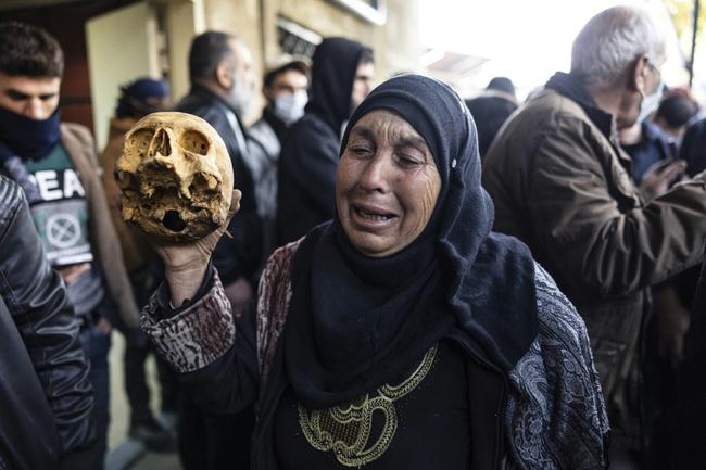 A woman holds a skull at a Damascus morgue where people are trying to identify the bodies of relatives abducted under Assad