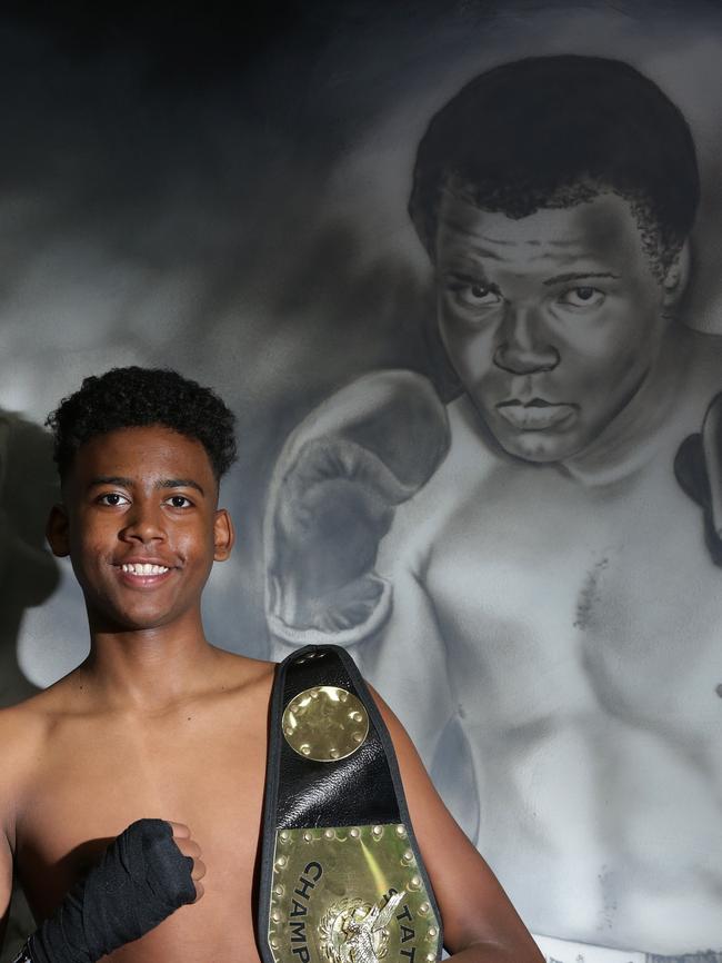 Omer next to the gym’s boxing hall of fame wall.