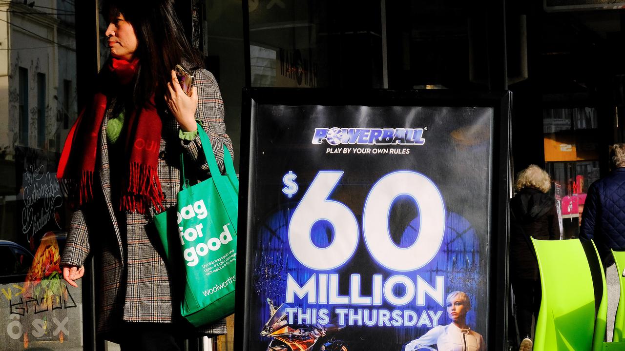 MELBOURNE, AUSTRALIA - NewsWire Photos JUNE 30, 2022: People walk past a billboard promoting tonight $60m Powerball, in Melbourne. Picture: NCA NewsWire / Luis Enrique Ascui