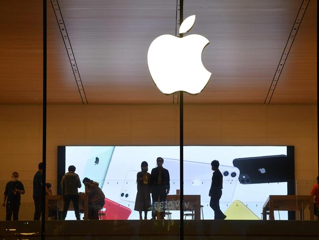 (FILES) In this file photo taken on October 19, 2020 people walk inside an Apple store in Beijing. - A steep drop in iPhone sales in the latest quarter cut Apple's profit by 7 percent to $12.7 billion, the company announced October 29, 2020, sending the company's stock reeling. (Photo by GREG BAKER / AFP)