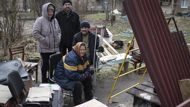 Bucha residents sit by a makeshift stove next to their wrecked apartment building on Monday. Picture: Getty Images