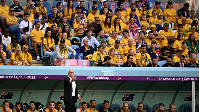 Graham Arnold gestures from the Socceroos bench as Aussie fans watch on.