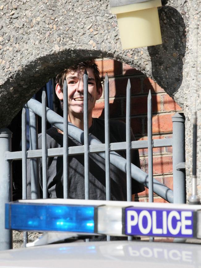 Cameron James Brasher smiles at the media from behind bars at the Launceston Magistrates Court.