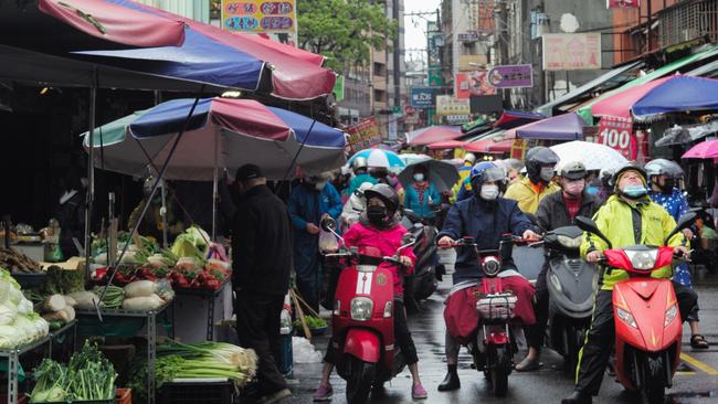 Motorcyclists ride past a traditional market in Shulin district, New Taipei City, on February 19, 2022. Picture: Sam Yeh/AFP