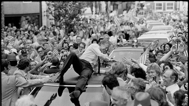 Then president Jimmy Carter leans across the roof of his car to shake hands along a parade route through a Kentucky town in 1979. Picture: Bob Daugherty/AP