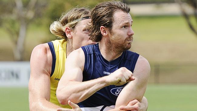 Patrick Dangerfield handballs under pressure from Mark Blicavs at Geelong training. Picture: Alan Barber