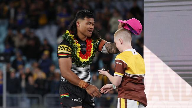 Brian To'o places a pink hat on a kid at the trophy ceremony. (Photo by Cameron Spencer/Getty Images)