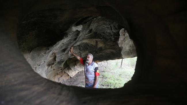 Wonnarua elder Uncle Warren Taggart at one of at least five Hunter Valley caves where thieves have chiselled out indigenous art dating back thousands of years. Picture by Peter Lorimer.