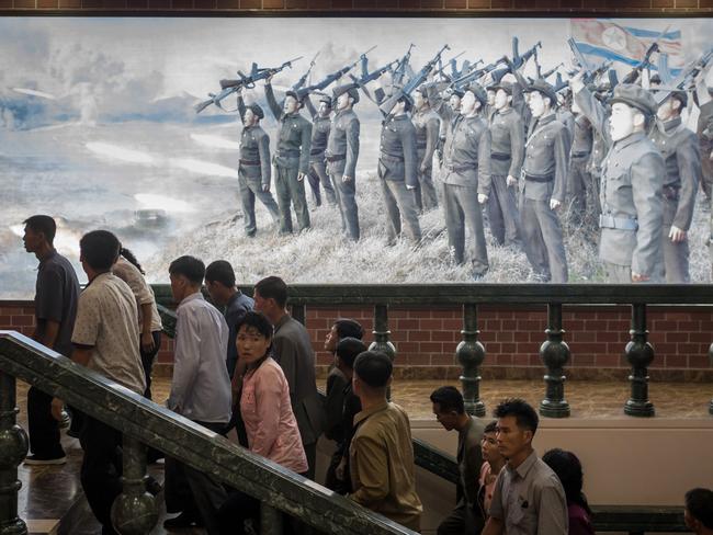 People walk up stairs before a propaganda poster showing Korean People's Army (KPA) soldiers at a museum in Sinchon, south of Pyongyang. North Korea says its latest ICBM tests are a “warning” targeting the US for its efforts to slap new sanctions. Picture: AFP