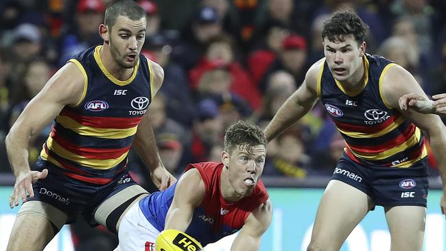 Jake Melksham gets his handpass out as Crows players Taylor Walker and Mitch McGovern watch on. Picture: Sarah Reed