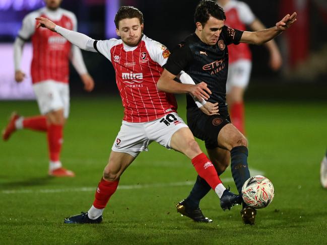 CHELTENHAM, ENGLAND - JANUARY 23: Eric Garcia of Manchester City is challenged by Alfie May of Cheltenham Town during The Emirates FA Cup Fourth Round match between Cheltenham Town and Manchester City at Jonny Rocks Stadium on January 23, 2021 in Cheltenham, England. Sporting stadiums around the UK remain under strict restrictions due to the Coronavirus Pandemic as Government social distancing laws prohibit fans inside venues resulting in games being played behind closed doors. (Photo by Shaun Botterill/Getty Images)