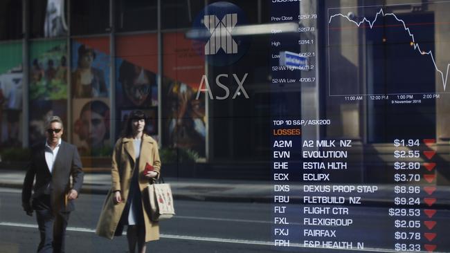 Pedestrians are reflected against an electronic board displaying stock information inside the ASX in Sydney. Picture: Bloomberg