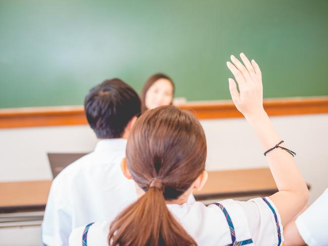 Chinese students, one female and two male, and their teacher during lesson at a Hong Kong School, University, China, Asia. The girl is raising her arm. Nikon D800, full frame, XXXL.