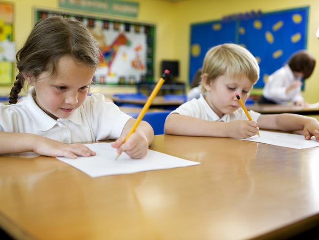 A pair of cute 5 year-old primary school children working hard on their studies in the classroom.