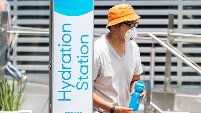 A man wearing a face mask fills up a water bottle. Picture: AFP