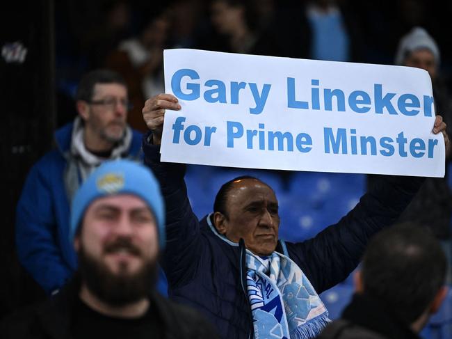 A Manchester City fan holds a banner reading 