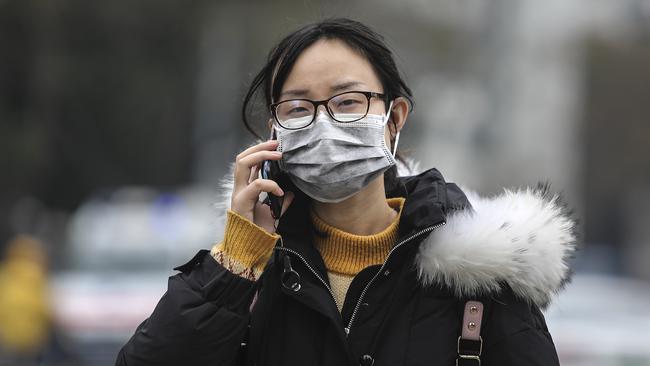 A woman wears a mask while walking past Wuhan’s closed Huanan Seafood Wholesale Market, which has been linked to cases of coronavirus.