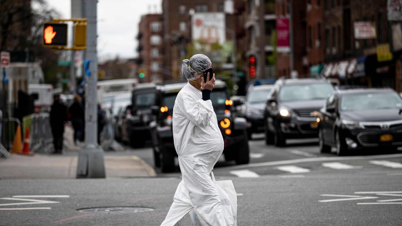 A pregnant woman wearing a hazmat suit and a mask walks in Queens. Picture: AFP/Johannes Eisele