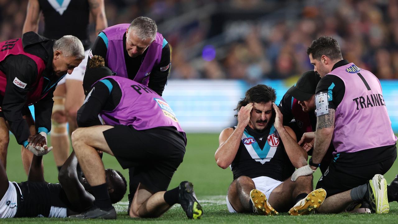 Aliir and Jones in the hands of trainers. (Photo by Sarah Reed/AFL Photos via Getty Images)