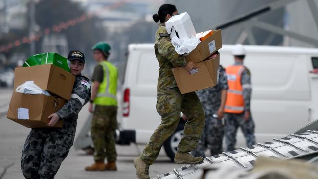 Army and navy personnel load supplies onto HMAS Adelaide as it prepares to help with the bushfire crisis. Picture: Bianca De Marchi