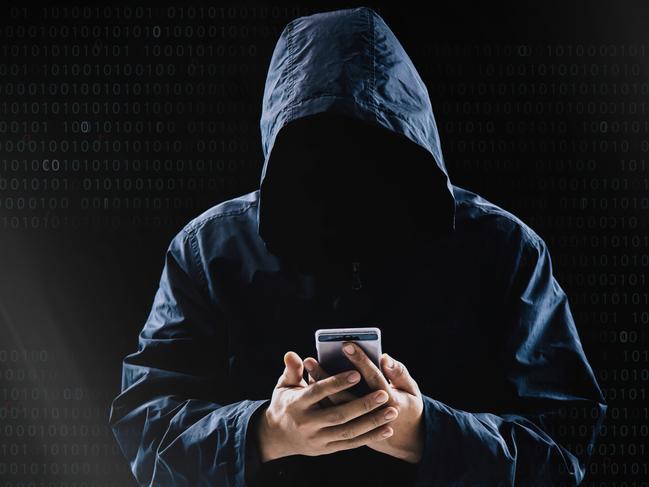 Internet crime concept,Hooded hacker using smartphone in dark room istock image