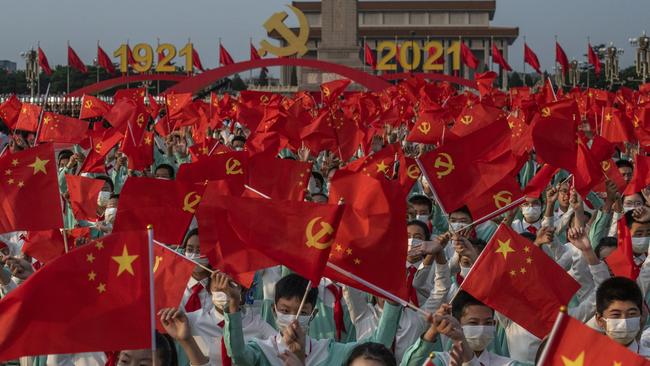 Chinese students wave party and national flags at a ceremony marking the 100th anniversary of the Communist Party in Beijing on Thursday. Picture: Getty Images