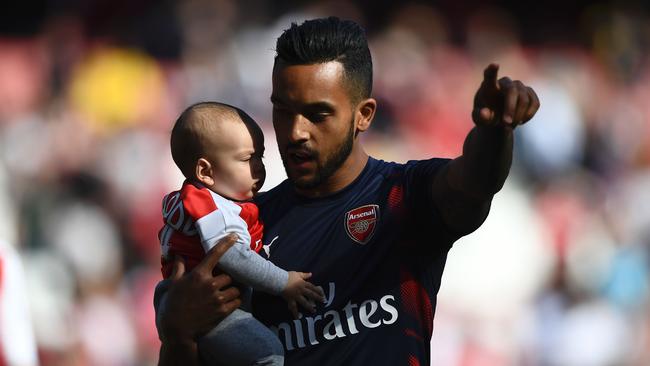 Arsenal's English midfielder Theo Walcott (R) stands on the pitch with his son Arlo (L).