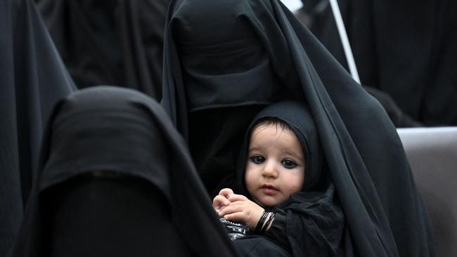 A woman carries her child as they listen a speaker before a pro-Taliban rally at the Shaheed Rabbani Education University in Kabul over the weekend. Picture: AFP