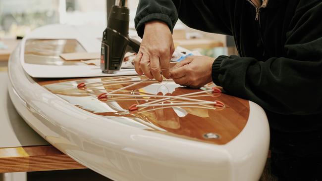 A craftsman at Hermès Ateliers Horizons puts the finishing touches on a bespoke paddleboard. Pictures: Florent Tanet, Marvin Leuvrey