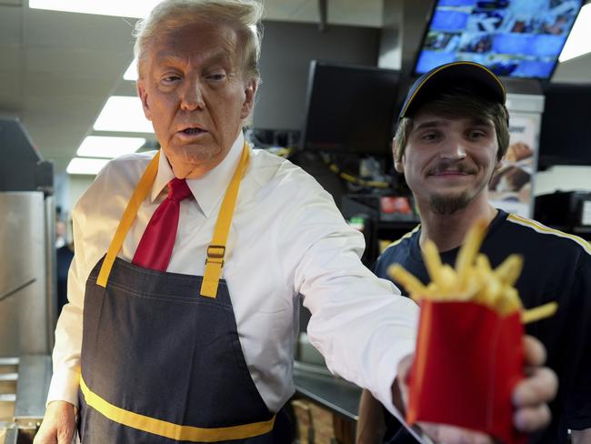 Republican presidential nominee former President Donald Trump, left, hands off an order of fries after working alongside an employee during a visit to McDonald's in Feasterville-Trevose, Pa., Sunday, Oct. 20, 2024. (Doug Mills/The New York Times via AP, Pool)