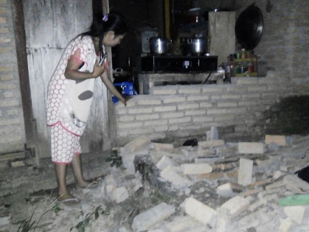 A resident is seen beside the collapsed brick wall of her house at Tobadak village in Central Mamuju, western Sulawesi province. Picture: AFP