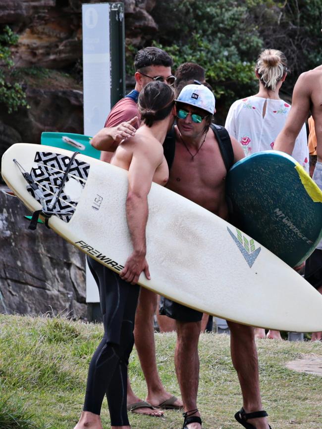 Two surfers exchange hugs on the Bondi to Bronte walk around McKenzies beach on Sunday. Photographer: Adam Yip