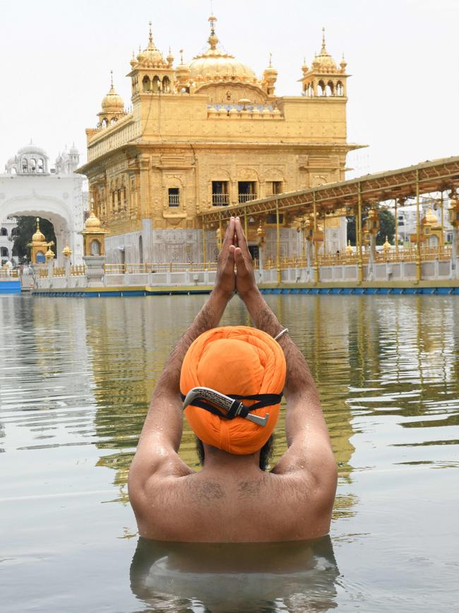 A Sikh devotee takes a dip in the holy sarovar (water tank) at the Golden Temple in Amritsar in the Indian state of Punjab. Residents of Punjac can see the Himalayas for the first time in 30 years. Picture: AFP