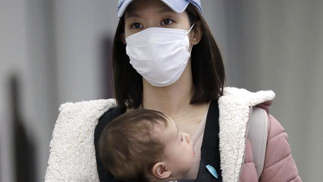 A woman wears a protective mask as she holds a baby while she walks through O'Hare International Airport in Chicago. Picture: AP