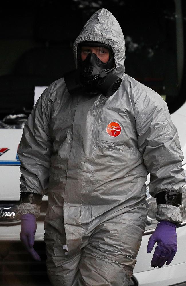 Military personnel wearing protective coveralls work to remove a vehicle as part of the ongoing investigation. Picture: AFP