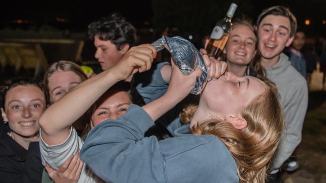 Schoolies look on as a girl skolls a sack of cask wine. Picture: Jason Edwards