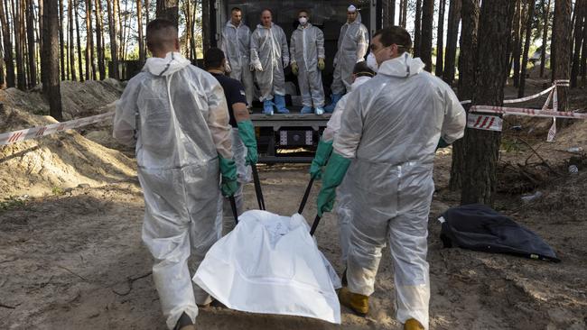 Rescue workers carry bodies from unidentified makeshift graves at the eastern Ukraine town of Izyum. Picture: Getty Images