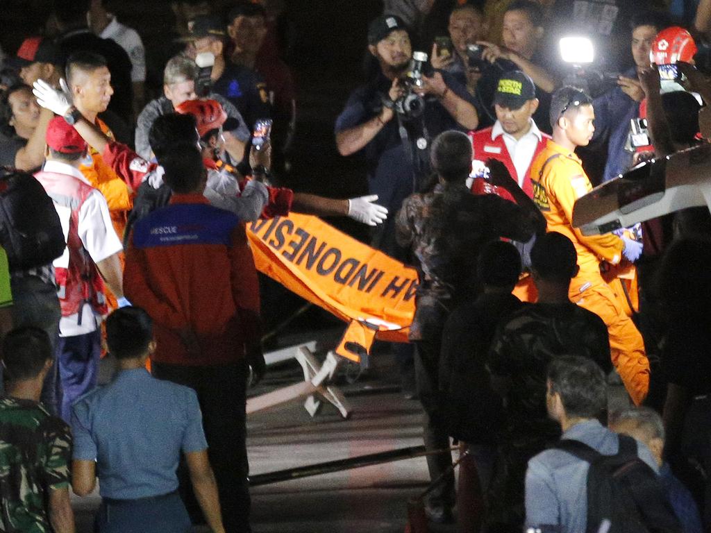 Rescuers carry a body bag containing the remains recovered from the area. Picture: AP